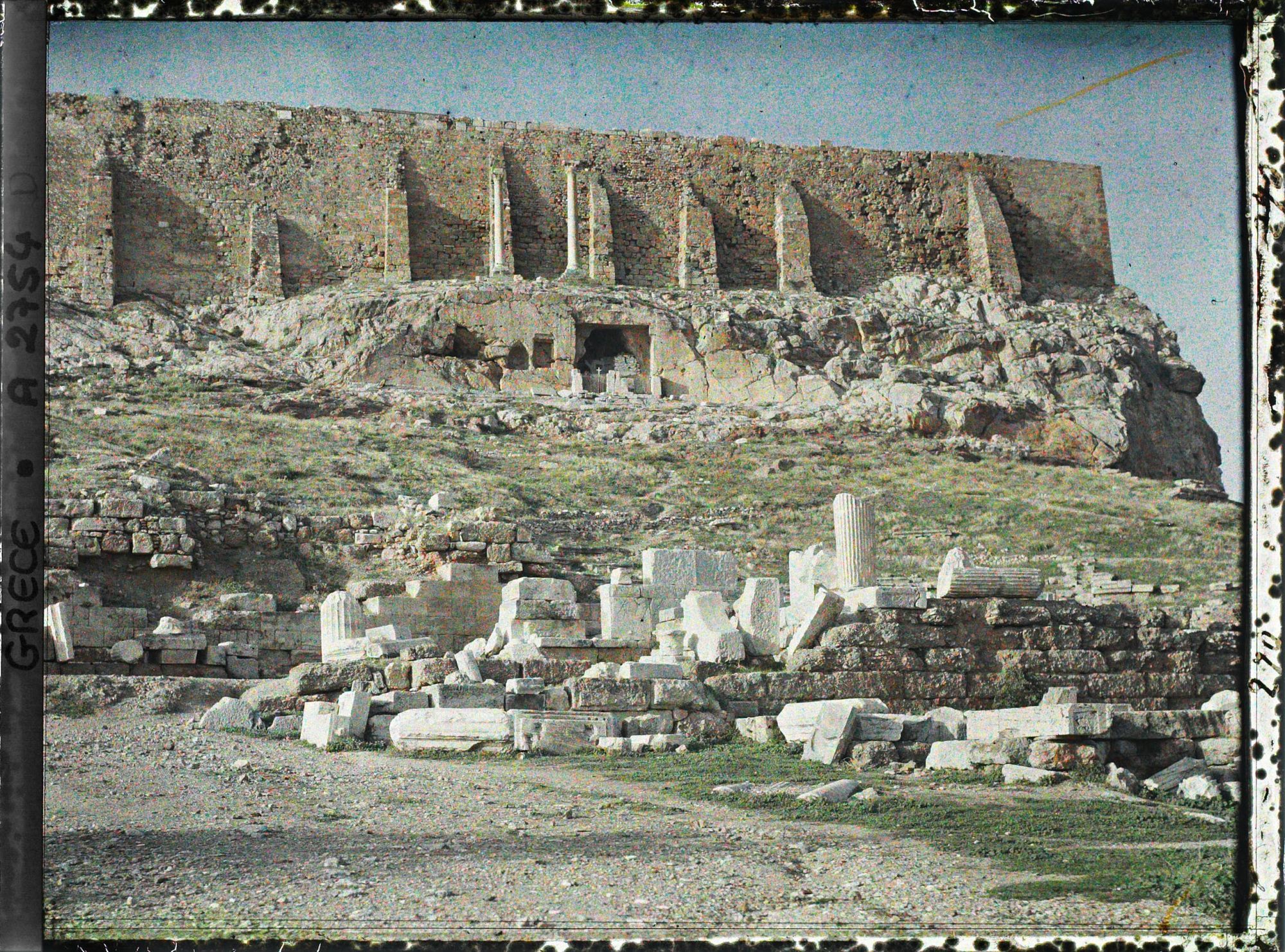 Image représentant Vestiges de l'arrière scène du Théâtre de Dyonisos. Au-dessus, sous le mur sud de l'Acropole, la chapelle de la Vierge de la grotte