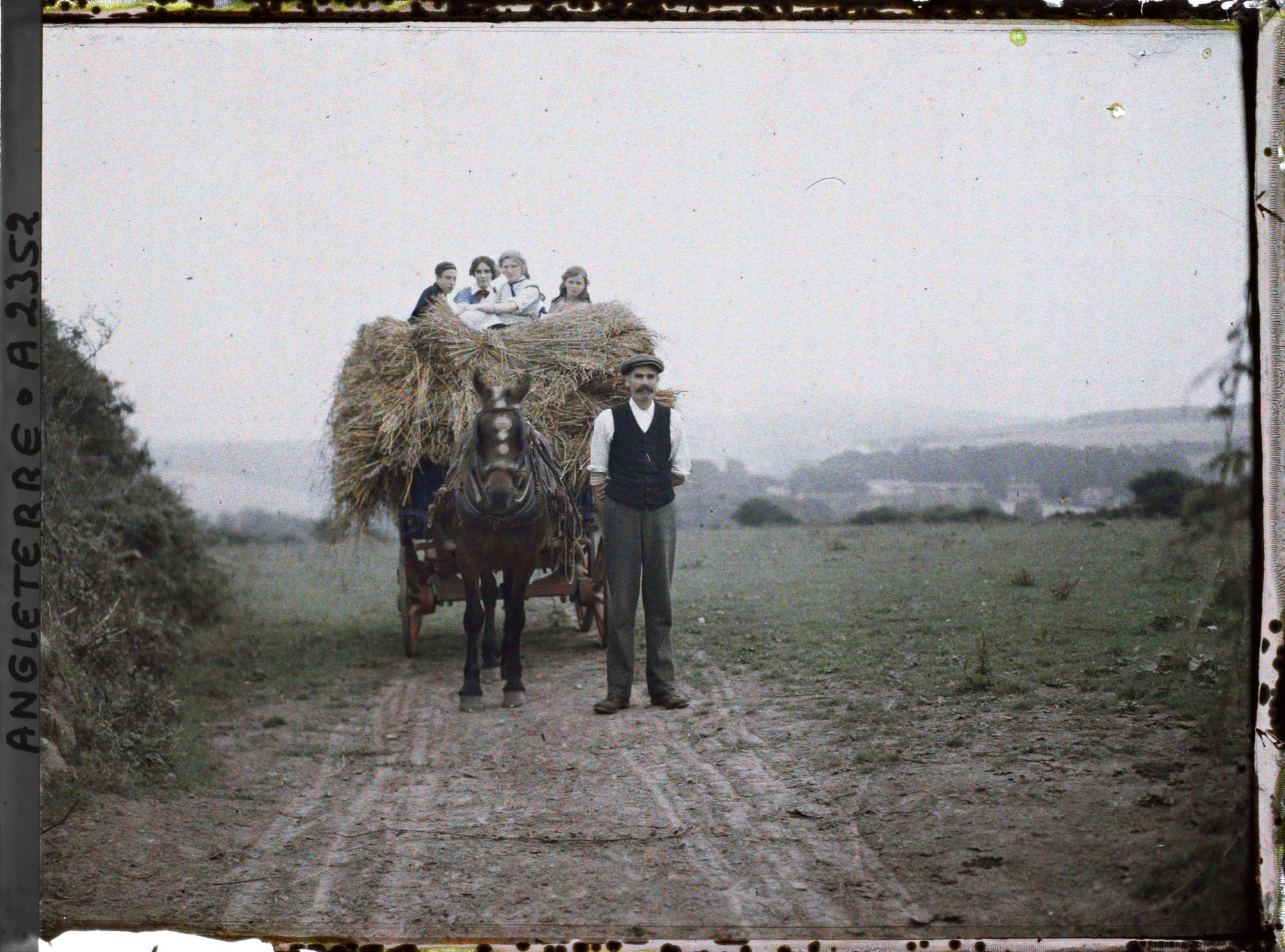 Image représentant Agriculteur près d'une charrette de fourage, accompagné de jeunes gens