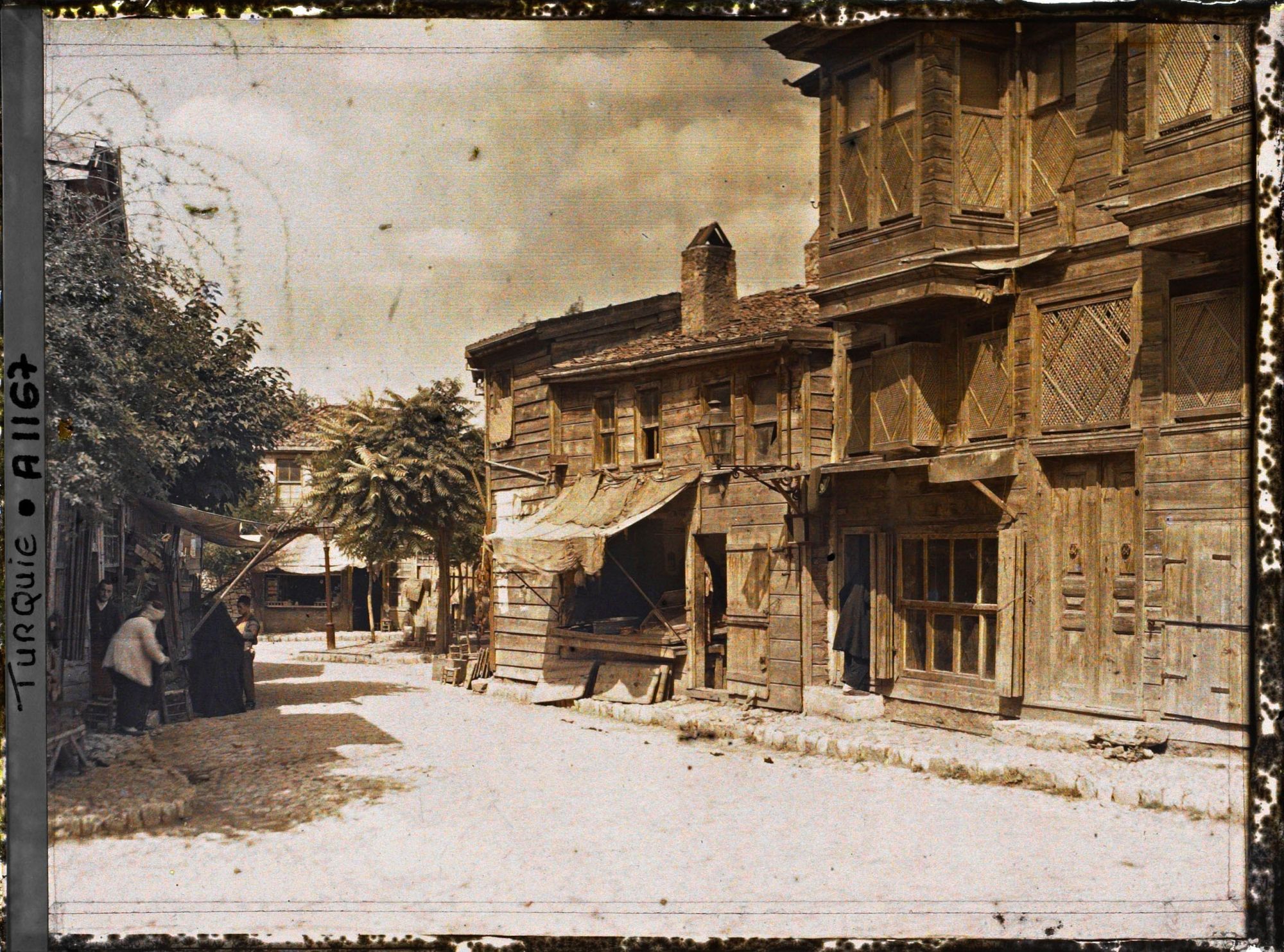 Image représentant Une rue bordée de constructions en bois avec des échoppes en rez-de-chaussée et les habitations à l'étage