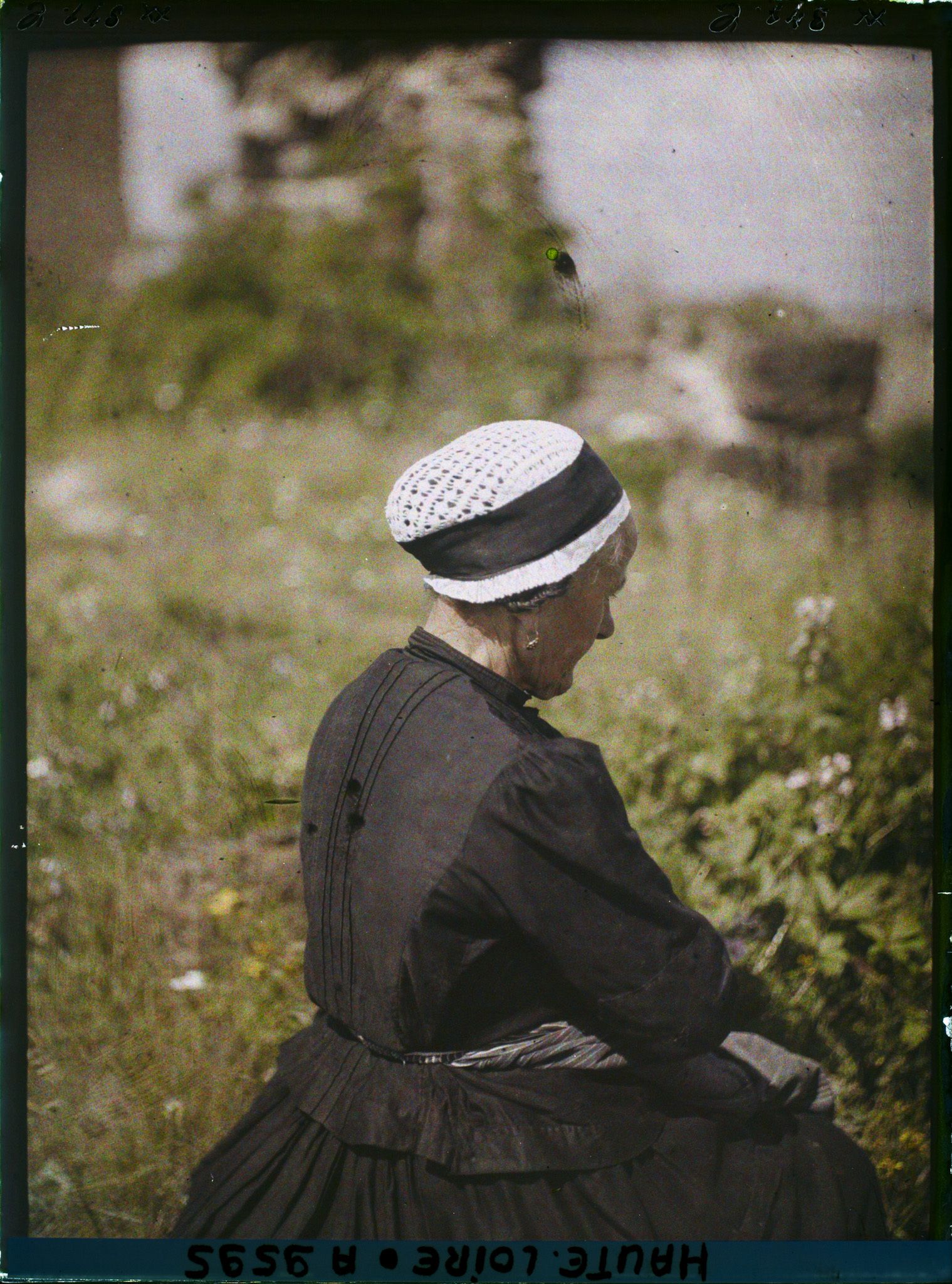 Image représentant Femme de profil portant un bonnet traditionnel du Puy en dentelle et ruban