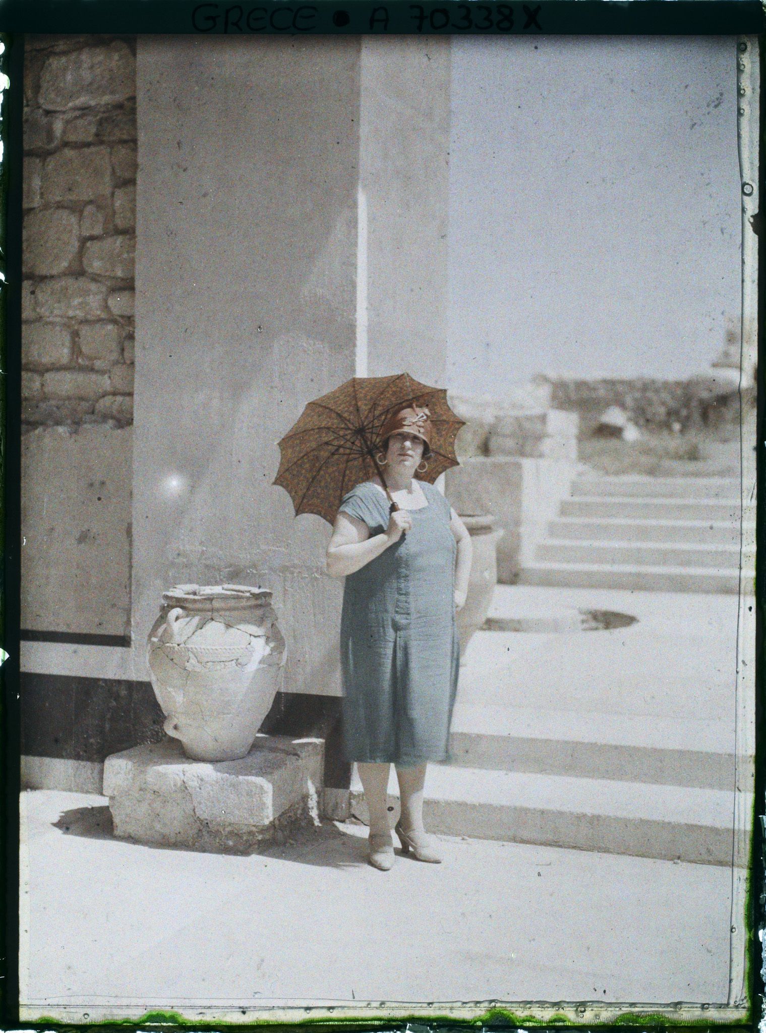 Image représentant Femme d'une quarantaine d'années élégamment vêtue au pied des Propylées sud (guide, interprète, compagne de l'opérateur ?)