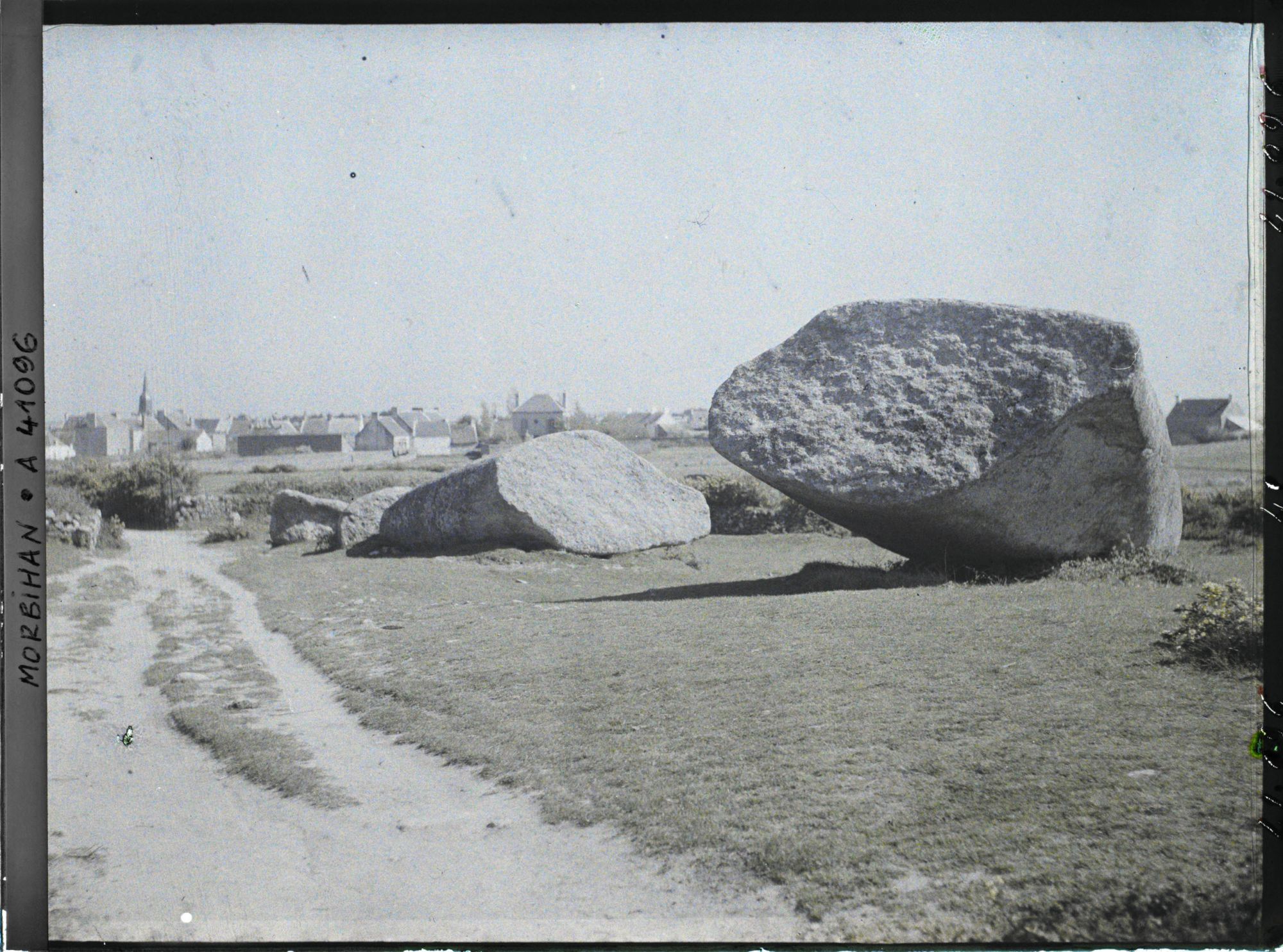 Image représentant Le Grand Menhir brisé ; à l'arrière-plan, le village de Locmariaquer