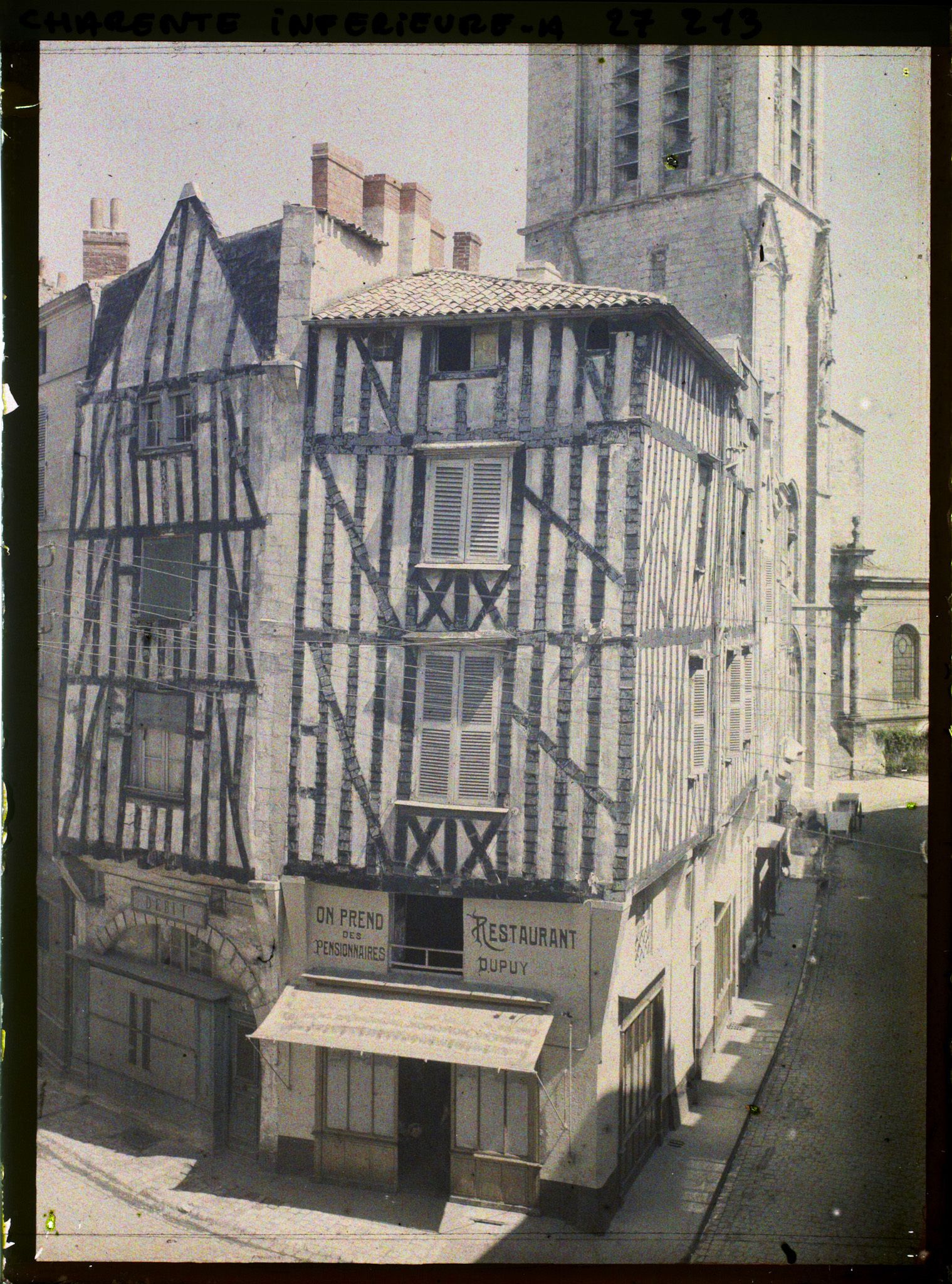 Image représentant Maison à colombages, le restaurant Dupuy à l'angle de la rue de la Bletterie et la rue Saint-Sauveur, au fond l'église Saint-Sauveur