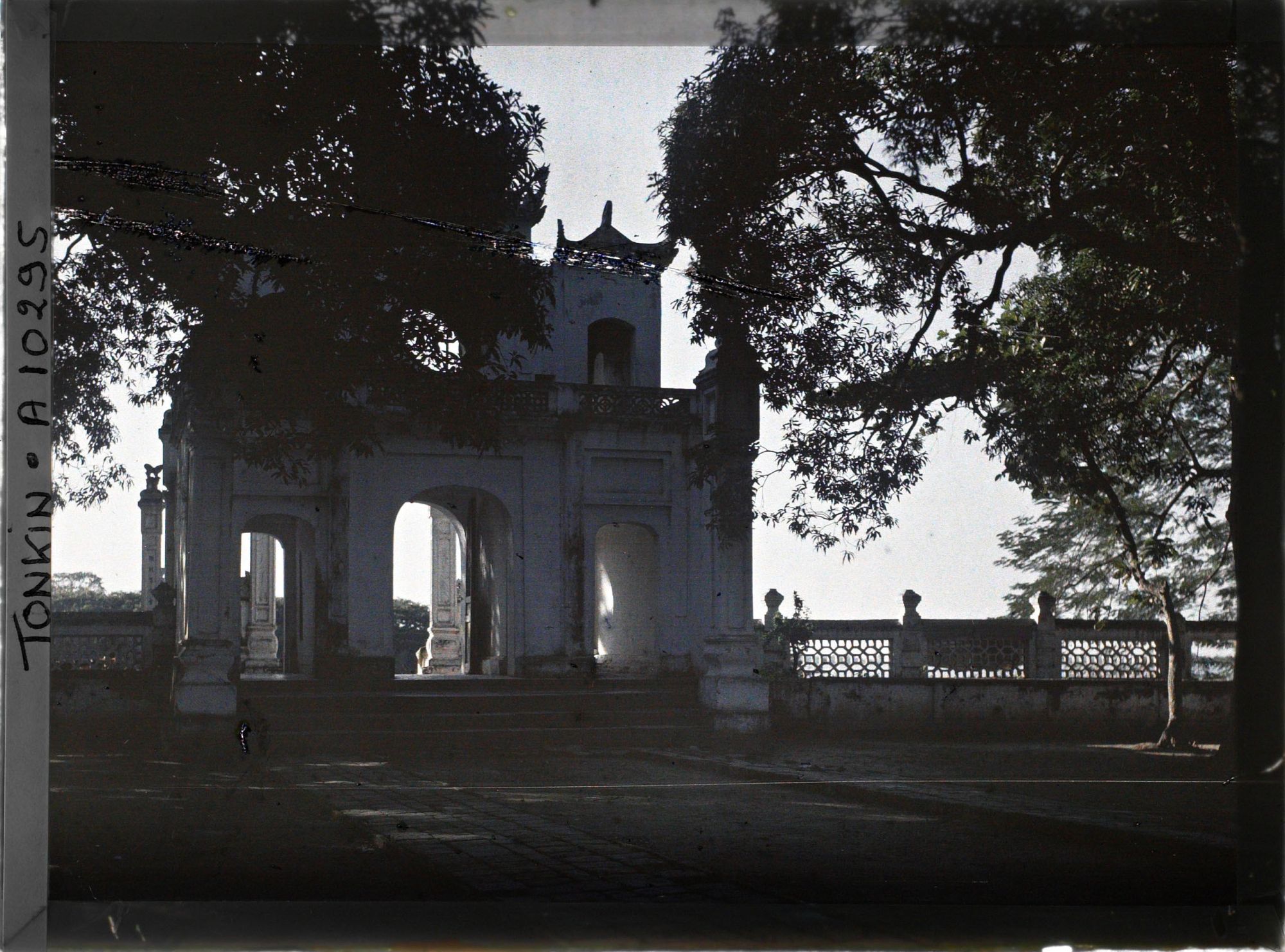 Image représentant Le portique d'entrée vu en contre-jour depuis l'intérieur de la cour plantée de manguiers, du temple de Chan-vu (ou Tran-vu)