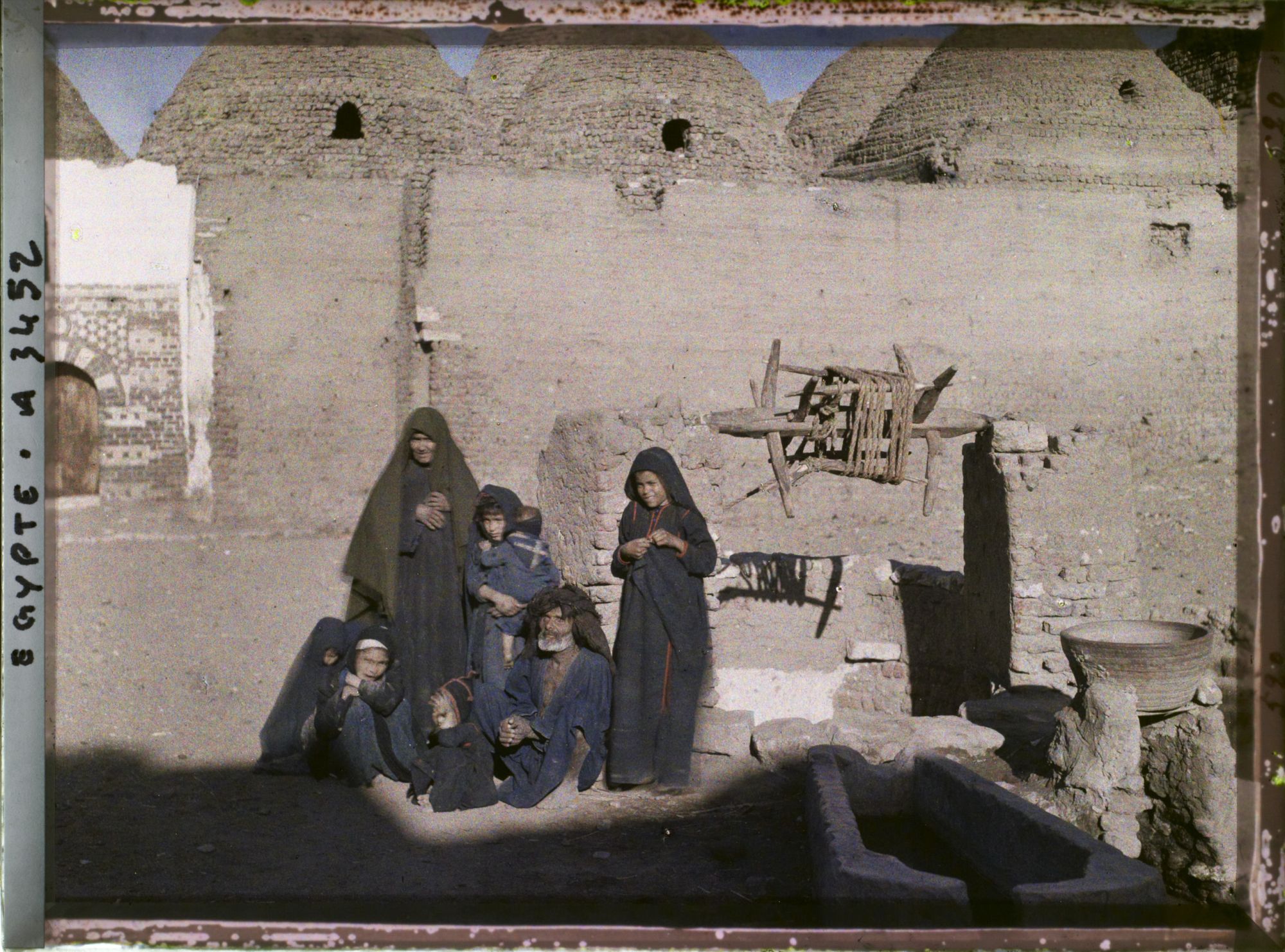 Image représentant Un couple de vieillards et des jeunes enfants à côté d'un puits devant l'église copte Béni Mansour