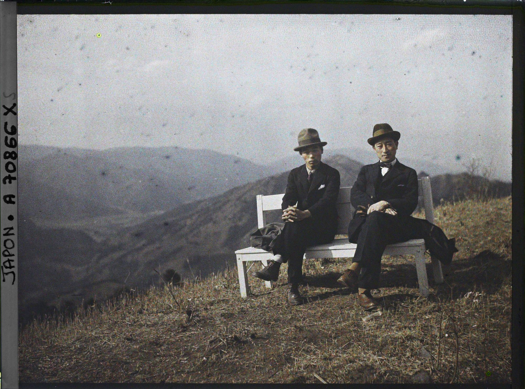 Image représentant Mont Hiei : Deux hommes sur un banc devant la vue vers la vallée d'Ohara et Yase