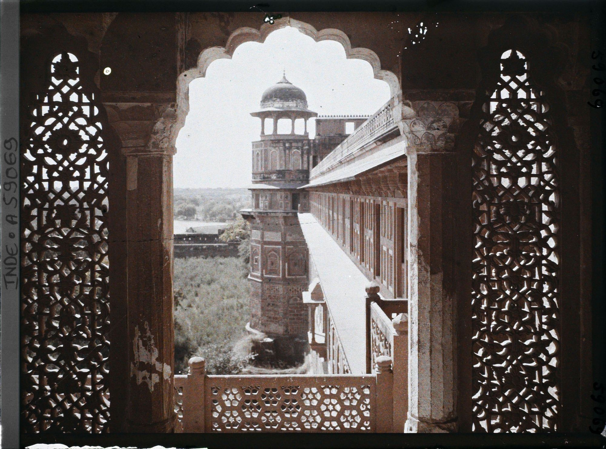Image représentant Tour extérieure surmontée d'un chhatri, vue d'une fenêtre encadrée de jalis (dentelle de pierre formant claustra) dans le fort Rouge (Lal Qila)
