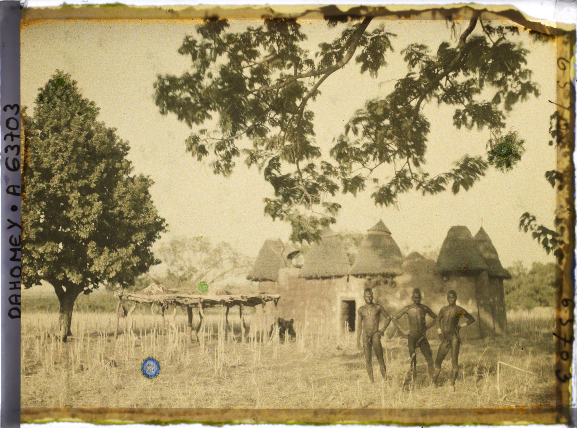 Image représentant Trois hommes somba devant un tata (case) et une plate-forme à sécher le mil