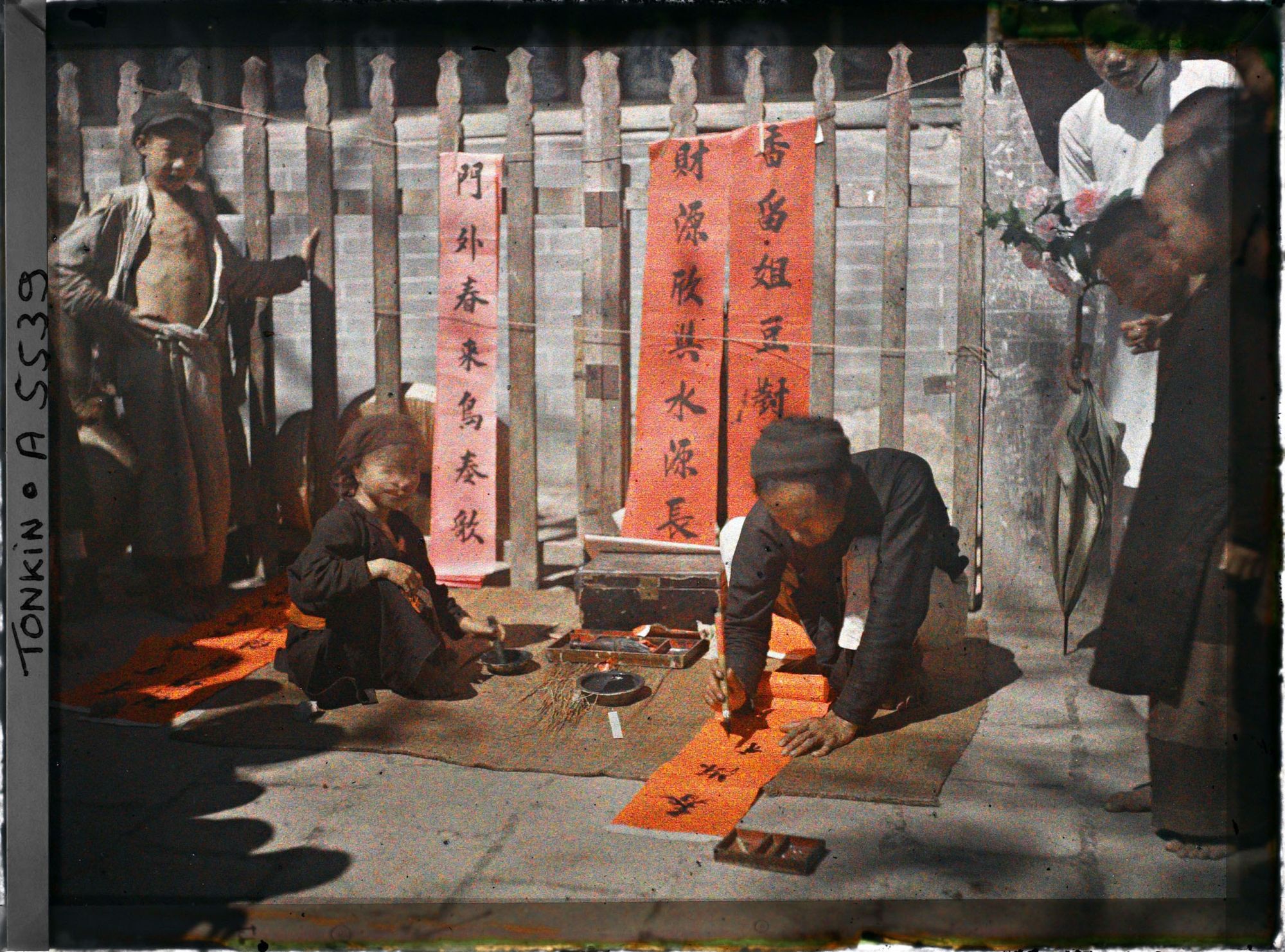 Image représentant Un artisan calligraphiant des " sentences parallèles " en vente à l'époque de la fête du Têt
