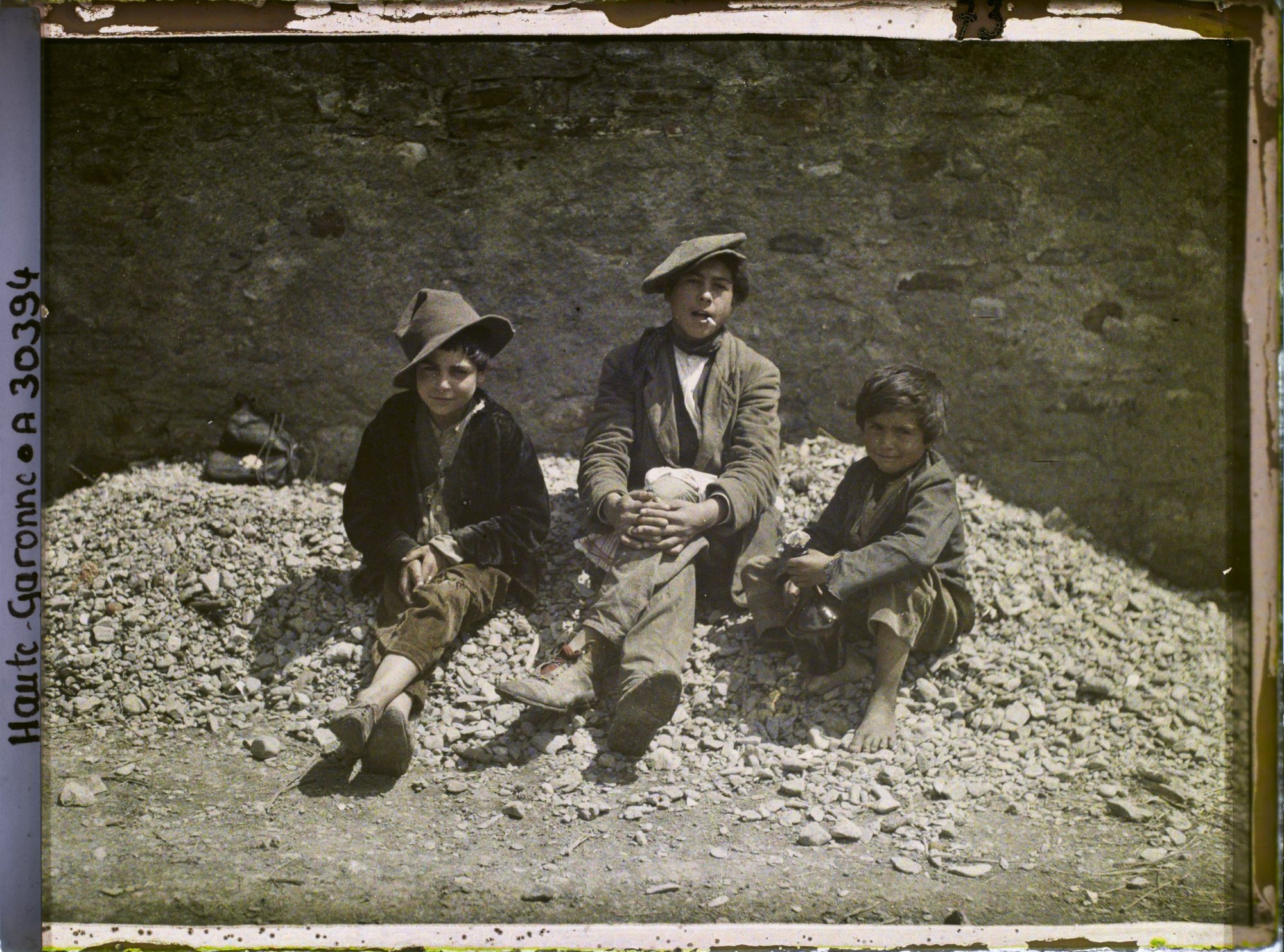 Image représentant Trois enfants espagnols assis sur des cailloux