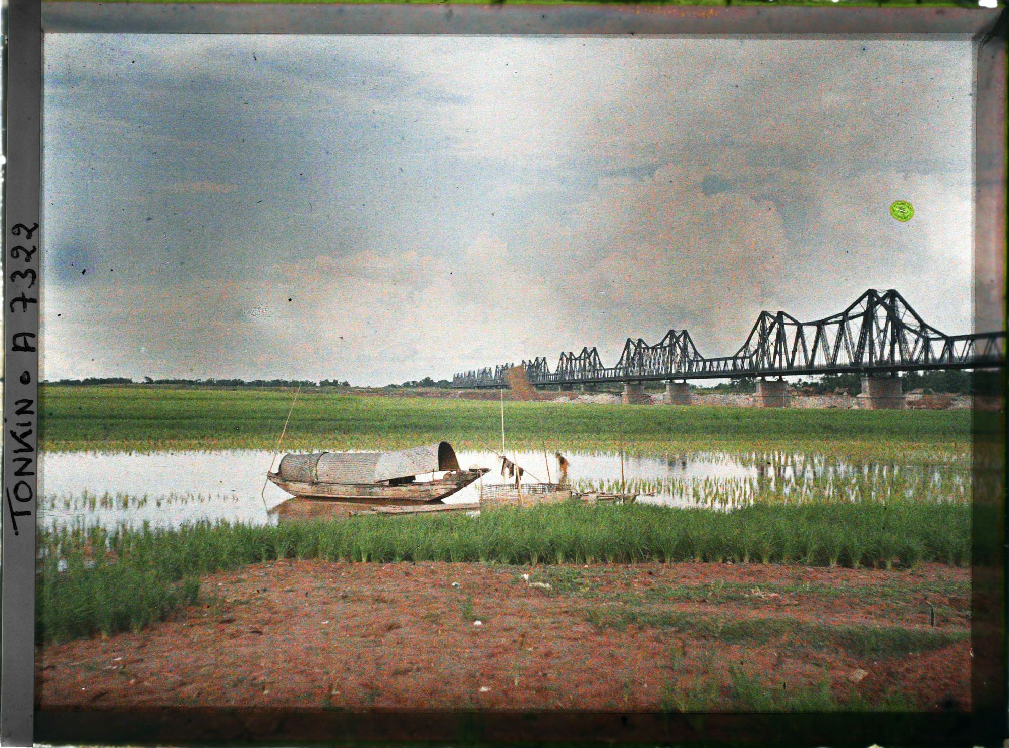 Image représentant Des rizières et un sampan au bord du Fleuve Rouge, près du pont Doumer