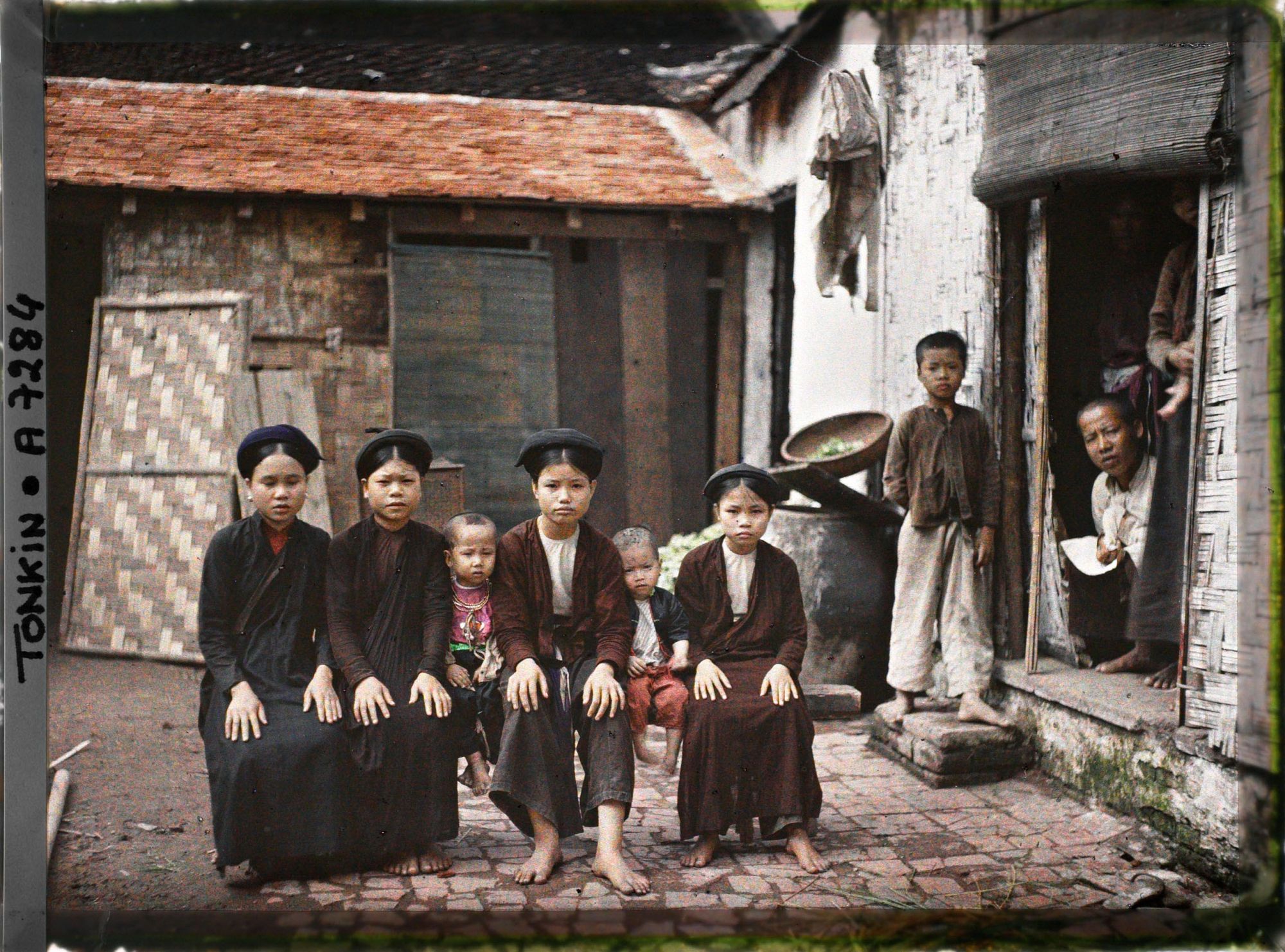 Image représentant Des jeunes filles et des enfants de classe aisée, assis sur un banc dans la cour intérieure d'une habitation