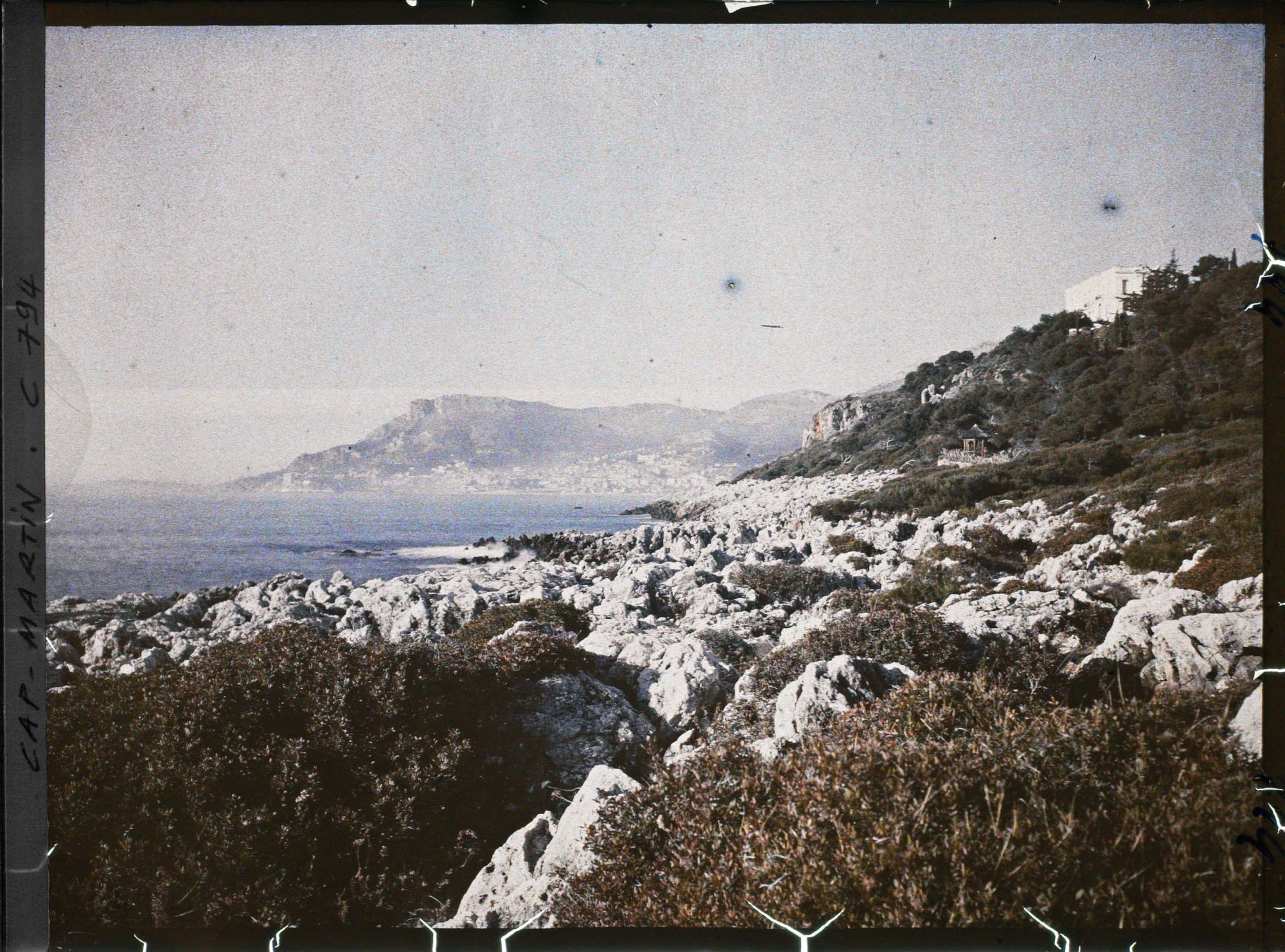 Image représentant La villa Kahn dite villa Zamir, vue depuis le rivage où roches et végétation se mêlent