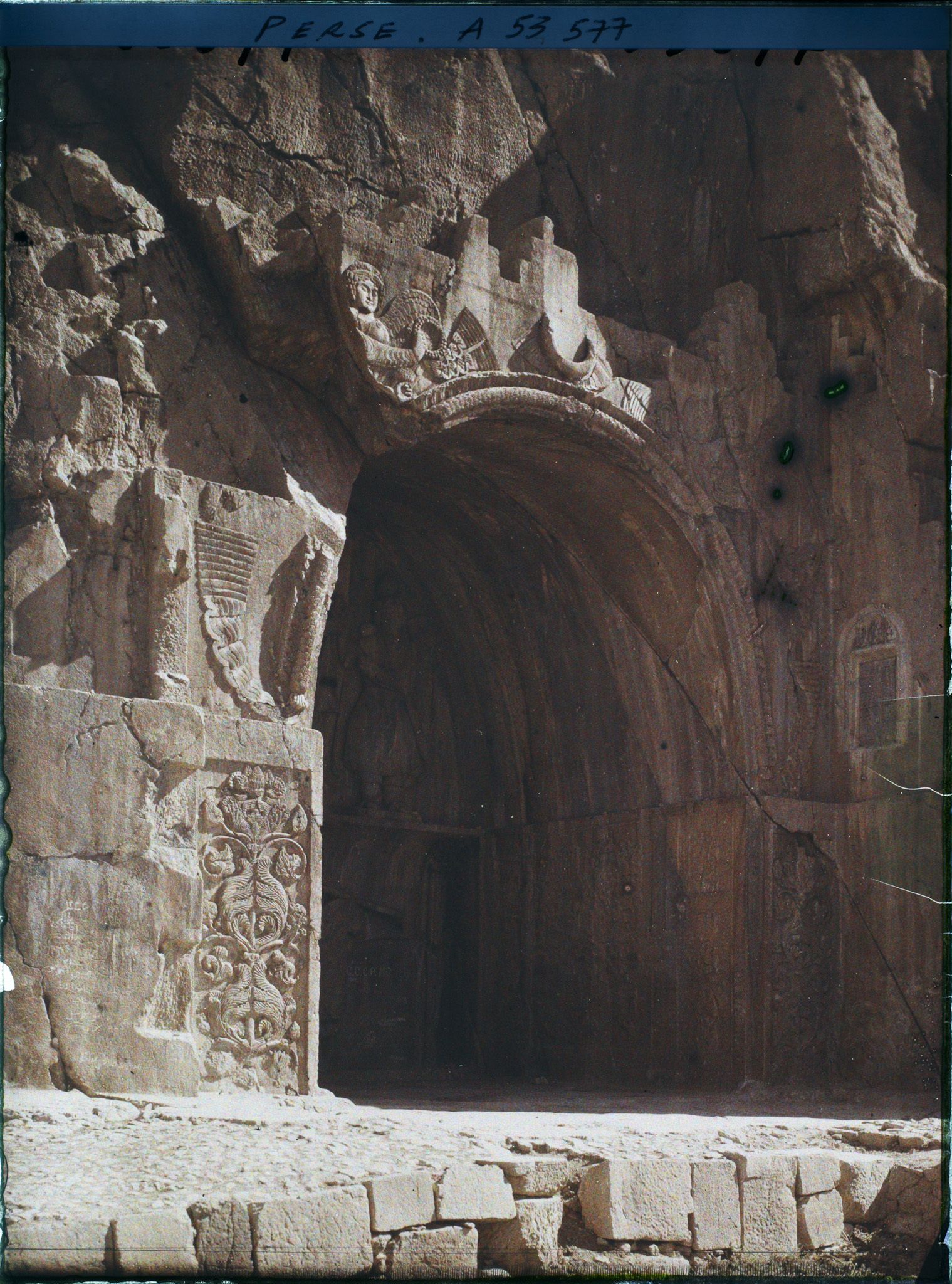 Image représentant La grande grotte, celle de Khosro II. Au-dessus de la voûte, figure ailée d'inspiration romaine portant l'anneau du pouvoir et le diadème royal