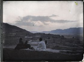 Image représentant Panorama sur la ville avec trois personnes assises sur le bord d'une terrasse, vers le soir