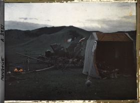 Image représentant La tente de l'opérateur et les deux voitures dételées près d'un feu destiné sans doute à la cuisson du repas