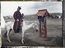 Image représentant Un lama à cheval près d'un petit monument votif