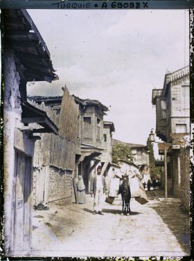 Image représentant Un homme menant un mulet lourdement chargé dans une rue d'un quartier populaire