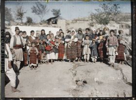 Image représentant Groupe d'habitants et femmes à tabliers tissés devant les décombres de leur village