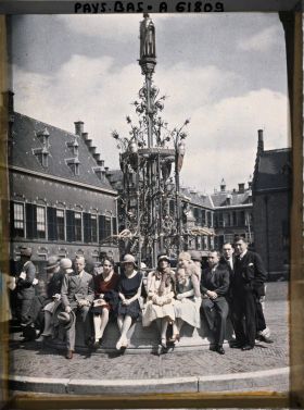 Image représentant Groupe de journalistes assis sur la margelle de la fontaine en fer forgé, érigée par Cuyper, portant la statue du comte Guillaume II par Jünger