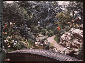 Image représentant Pont du " sanctuaire japonais " reliant un chemin bordé de roches à une rive fleurie