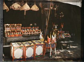 Image représentant Un étalage d'objets votifs et / ou de jouets (?) devant une boutique dans le quartier sino-annamite (?)