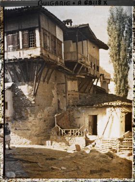 Image représentant Rue de terre battue jonchée de paille ou cailloux, morceaux de bois et maisons en étages