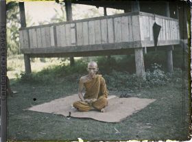 Image représentant Un bonze assis en méditation sur une natte, près de la bonzerie