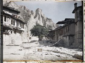 Image représentant Rue de terre battue et cailloux, jonchée de débris et bordée de maisons, menant à des caves à vin, creusées dans la falaise
