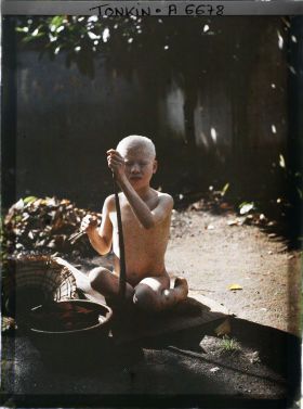 Image représentant Un jeune albinos, assis sur une natte