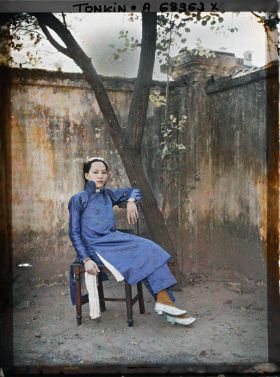 Image représentant Une métisse chinoise assise sur une chaise, de trois quarts, dans un angle de cour