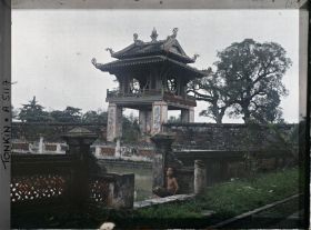 Image représentant Un enfant assis au bord du bassin quadrangulaire Thien-quang-tinh (" puits où se reflète l'éclat pur du ciel "), derrière lequel se détache le Khue-van-cac (Kiosque de la Littérature)