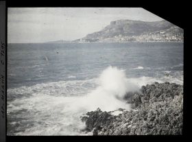 Image représentant Monaco vu depuis des rochers de la promenade du cap sur lesquels se brisent les vagues