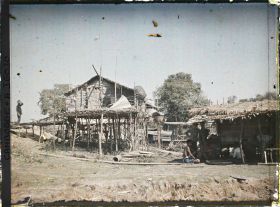 Image représentant Une maison sur pilotis et, à droite, pâtisserie tenue par des Vietnamiens
