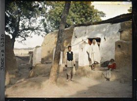 Image représentant Deux hommes et une enfant devant la plus belle maison du village