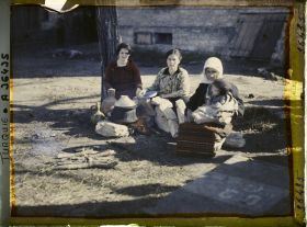 Image représentant Un groupe de femmes grecques dont l'une tenant un enfant près d'un foyer improvisé