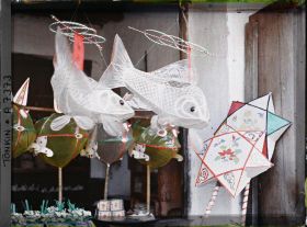 Image représentant Un étalage de jouets en papier huilé devant une boutique, dans la " rue du Chanvre "