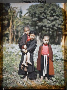 Image représentant Une jeune fille en turban tenant par la main deux enfants de moins de douze ans