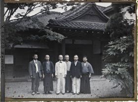 Image représentant Groupe d'hommes, les uns en vêtements traditionnels, les autres habillés à l'occidentale, devant une résidence non identifiée