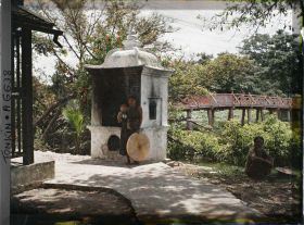 Image représentant Une femme et enfant devant un édicule près de la passerelle conduisant au temple Ngoc-so'n (appelé par les Européens "Pagode des Pinceaux") situé sur "l'île de Jade" du Petit Lac