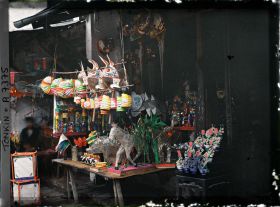 Image représentant Un étalage de jouets en papier huilé devant une boutique, dans la " rue du Chanvre "