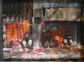 Image représentant Un artisan calligraphiant des " sentences parallèles " en vente à l'époque de la fête du Têt