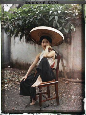 Image représentant Une jeune femme du peuple en pantalon ample et cache-sein, coiffée du grand chapeau en feuilles de latanier