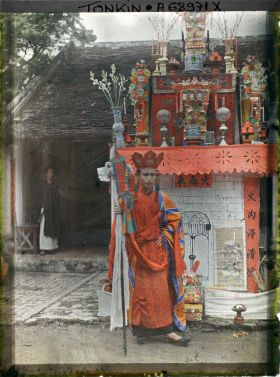 Image représentant Le Thay-phu-thuy devant l'édicule symbolisant la prison infernale aux portes gardées par des images de démons