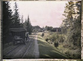 Image représentant Andeers Beer Wilse prenant une photographie près de la voiture de location, arrêtée sur une route à l'entrée d'un village