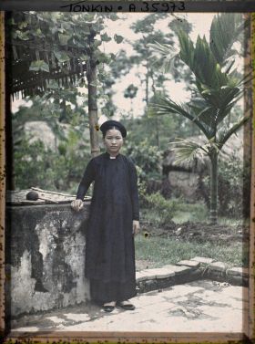 Image représentant Jeune fille de classe aisée, devant un puits, surmonté d'une pergola couverte de bétel grimpant