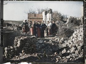 Image représentant Groupe de femmes et d'enfants au milieu des décombres du village ravagé par la guerre