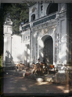 Image représentant Un homme et un groupe d'enfants assis devant le portique d'entrée du temple Chan-vu (ou Tran-vu) dans le quartier de la Citadelle (le Grand Lac)