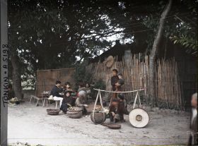 Image représentant Des marchands ambulants avec leurs palanches devant un restaurant en plein air