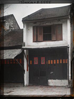 Image représentant La façade d'une maison aisée, décorée d'images peintes, au moment de la fête du Têt